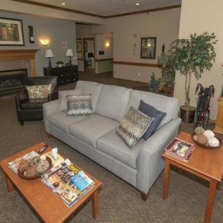 A cozy living room with a sofa, coffee table adorned with magazines, and a fireplace in the background.
