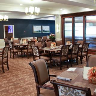 A well-furnished dining area with several tables and chairs, featuring elegant lighting and decor.