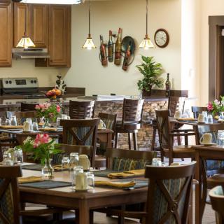 A cozy restaurant interior with neatly arranged tables and chairs, warm lighting, and decorative elements on the walls.
