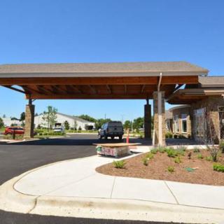 A modern building entrance with a wide carport and landscaped driveway.