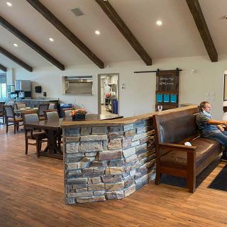 A cozy restaurant interior with a mix of booth and table seating, featuring a wooden floor and stone counter.