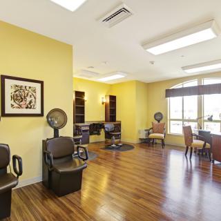 A bright salon interior with chairs and hairdryers, featuring yellow walls and natural lighting.