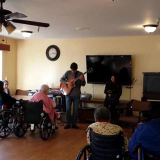 A musician performs for an audience in a nursing home.