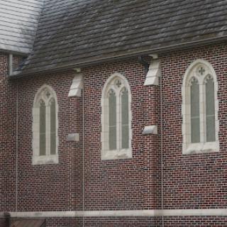 The intricate design of a brick church featuring gothic-style windows.