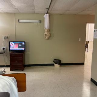 A view of a hospital room featuring a bed, television, and basic amenities.