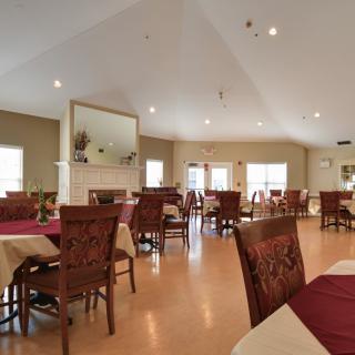 A well-lit dining room with multiple tables and chairs, designed for a spacious dining experience.