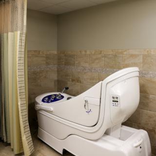 A specialized toilet designed for healthcare settings, equipped with a privacy curtain.