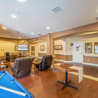 A cozy game room with a pool table, comfortable lounge chairs, and a television.