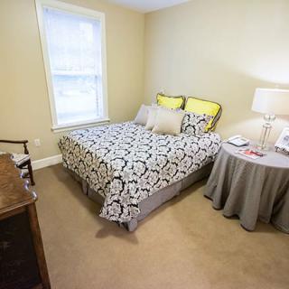 A cozy bedroom with a bed, side table, and a window.