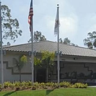 A building with flags in front and surrounded by trees.