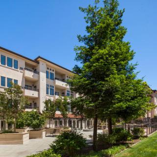 A residential apartment building with surrounding greenery under a clear blue sky.