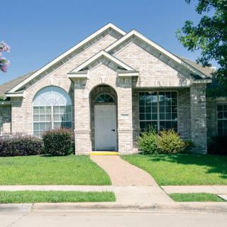A beautiful brick house with a well-maintained lawn on a sunny day.