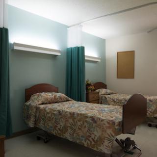 A hospital room featuring two beds with patterned bedding and privacy curtains.
