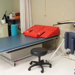 A physical therapy treatment room with a specialized table and equipment.