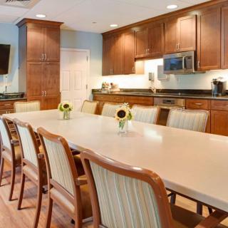 A spacious kitchen and dining area with a long table, chairs, and wooden cabinets.