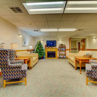 A cozy waiting room with sofas, chairs, a television, and a decorated Christmas tree.