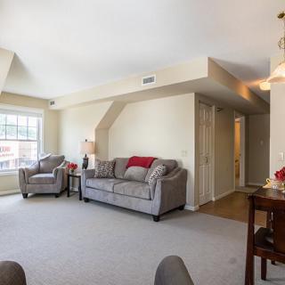 A cozy living room with a sofa, chair, and large window.