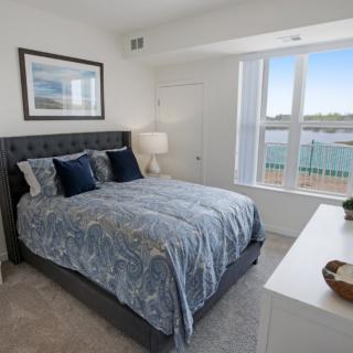 A cozy bedroom with a large bed, stylish bedding, and a bright window view.