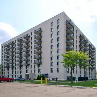 A multi-story apartment building with balconies and a surrounding parking area.