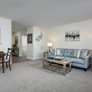 A modern living room with a cozy sofa, coffee table, and an adjacent dining area.