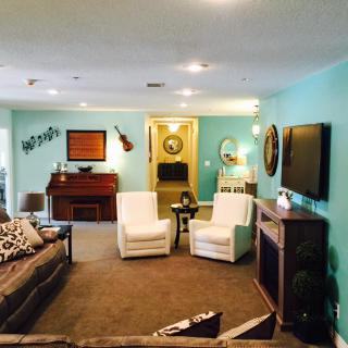 A cozy living room featuring a piano and guitar, with comfortable seating and vibrant decor.