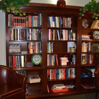 A cozy home library with a wooden bookshelf filled with books and decorative items.
