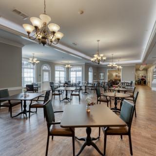 A spacious dining room featuring elegant chandeliers and neatly arranged tables and chairs.