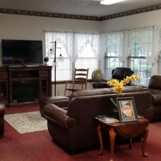 A cozy living room with leather sofas, a television, and large windows.