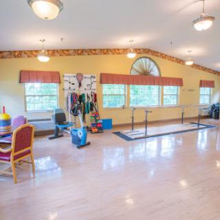 A spacious exercise room with various fitness equipment and large windows for natural light.