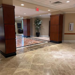 A well-lit hotel lobby featuring elegant wooden paneling and marble flooring.
