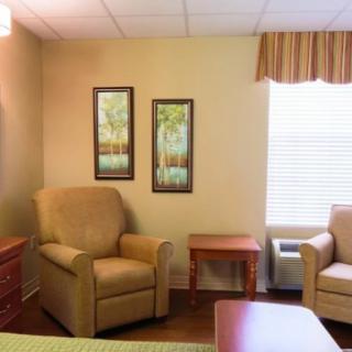 A cozy living room area with comfortable chairs, a small table, and framed artwork on the wall.