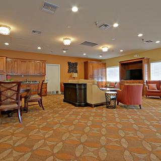 A cozy living room with a kitchen area, featuring comfortable seating and a television.