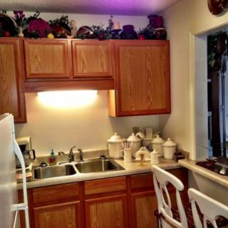 A cozy kitchen with wooden cabinets, a double sink, and decorative items on the counter.