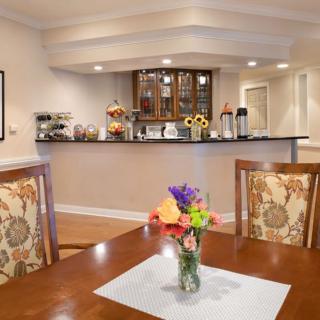 A cozy dining area with a floral arrangement on the table and a modern bar counter in the background.