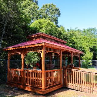 A beautifully crafted wooden gazebo surrounded by lush greenery.