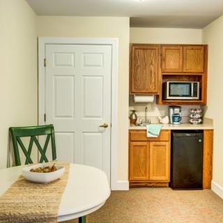A compact kitchenette with a mini fridge, microwave, and a small dining area.