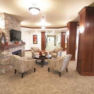 A cozy lobby area with a central seating arrangement, featuring upholstered chairs and a stone fireplace.