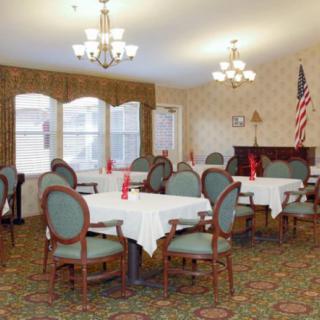An elegant dining room with neatly arranged tables, chairs, and chandeliers, featuring an American flag in the corner.