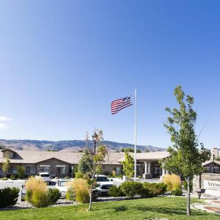 A suburban scene with a building, cars parked in front, and an American flag flying against a clear blue sky.