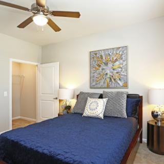 A cozy and stylish bedroom featuring a blue bedspread, modern furniture, and decorative wall art.