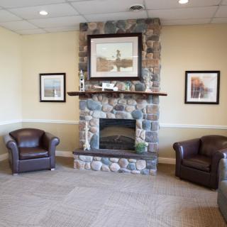 A cozy living room with a stone fireplace and leather chairs.