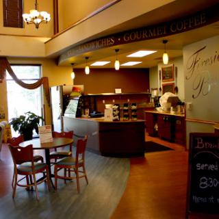 A cozy caf interior featuring a service counter, seating area, and warm lighting.