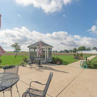 A sunny patio with outdoor seating and a gazebo, set against a cloudy sky.