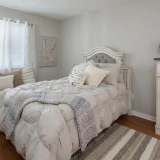 A cozy bedroom with a light color scheme and comfortable bedding.