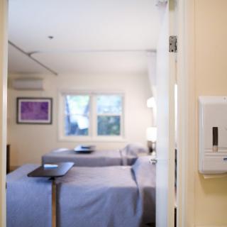 A well-lit hospital room featuring two beds and medical equipment.