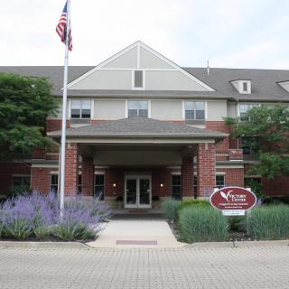 A brick building with an entrance, surrounded by landscaping and featuring a flagpole.