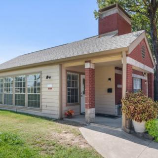 A small brick house with a porch and a well-maintained front yard.