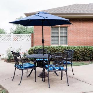 A cozy patio setup with a table, four chairs, and an umbrella in a backyard.