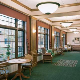 A spacious hallway with large windows, comfortable seating areas, and elegant lighting.