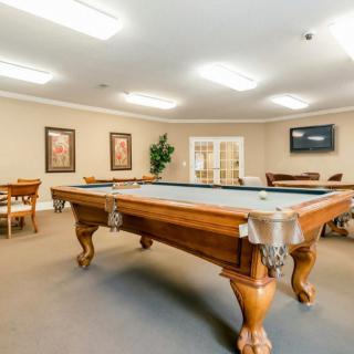 A well-lit game room featuring a classic pool table and seating area.